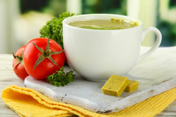 Cup of soup with bouillon cubes on wooden table — Stock Photo, Image