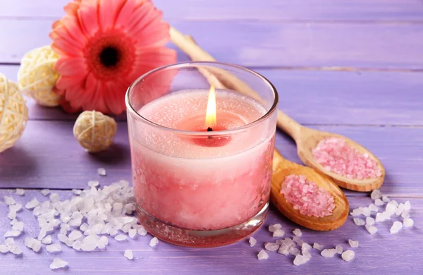 जांभळा लाकडी पार्श्वभूमीवर फुलांसह सुंदर गुलाबी मेणबत्ती — स्टॉक फोटो, इमेज