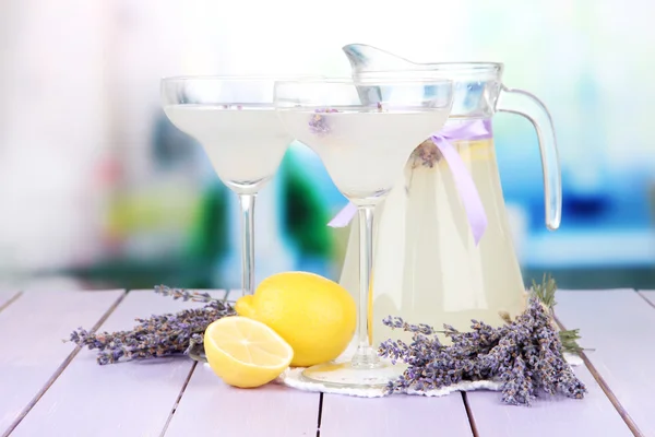 Limonada de lavanda em jarro de vidro e copos de coquetel, em fundo brilhante — Fotografia de Stock