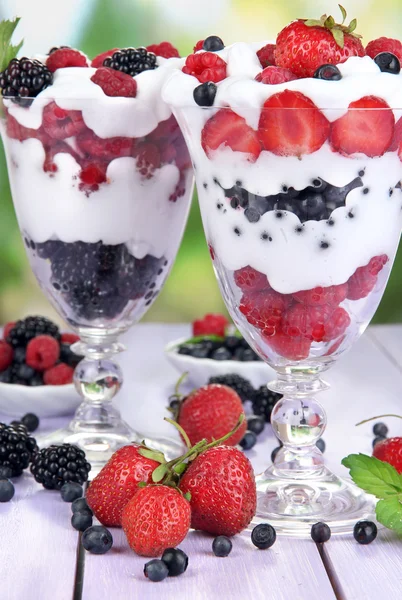 Natural yogurt with fresh berries on wooden table on green background — Stock Photo, Image