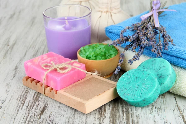 Bodegón con vela de lavanda, jabón, bolas de masaje, botellas, jabón y lavanda fresca, sobre fondo de madera — Foto de Stock