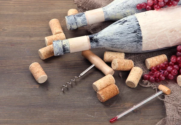 Staré lahve vína, vinných hroznů a zátky na dřevěné pozadí — Stock fotografie