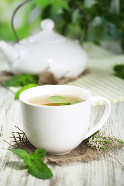 Teapot and cup of herbal tea with fresh mint on wooden table — Stock Photo, Image