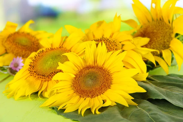 Bellissimi girasoli su tavolo di legno, su sfondo luminoso — Foto Stock