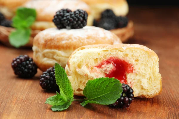 Tasty donuts with berries on wooden table — Stock Photo, Image