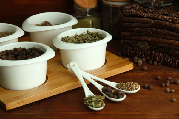 Assortment of spices in white spoons and bowls, on wooden background — Stock Photo, Image