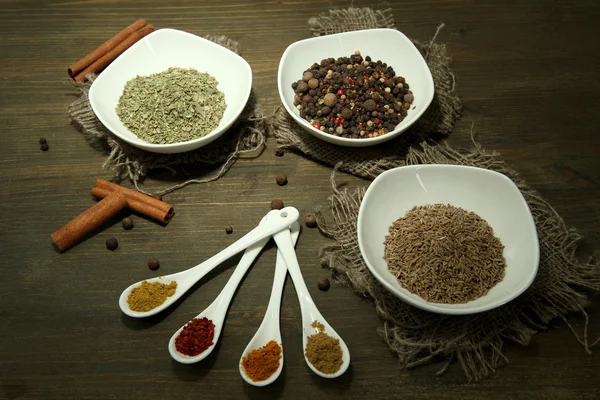 Assortimento di spezie in cucchiai bianchi e ciotole, su fondo di legno — Foto Stock