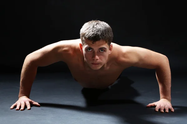 Bonito jovem desportista muscular, no fundo escuro — Fotografia de Stock