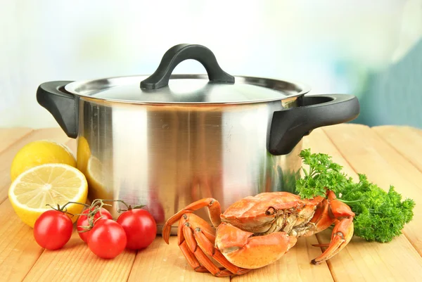 Composition with boiled crab, pan and vegetables on wooden table,on bright background — Stock Photo, Image