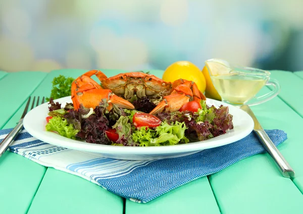 Gekookte krab op wit bord met salade bladeren en tomaten, op houten tafel, op lichte achtergrond — Stockfoto