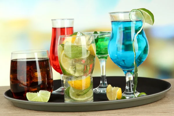 Many glasses of cocktails on tray on table, on bright background — Stock Photo, Image