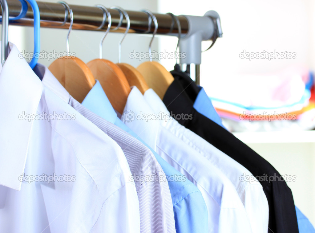 Variety of casual shirts on wooden hangers on shelves background