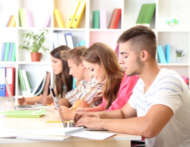 Kütüphanede oturan genç öğrenci grubu