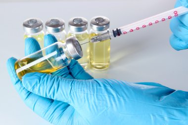 Tıp Şişeler ve gri arka plan üzerinde elinde şırınga