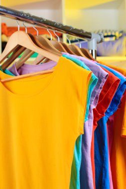 çeşitli ahşap askı raf arka plan üzerinde rahat t-shirt