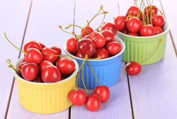 Bayas de cereza en cuencos sobre mesa de madera de cerca — Foto de Stock