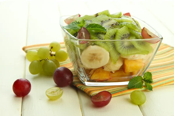 Вкусный фруктовый салат в стеклянной чаше, на белом деревянном столе — стоковое фото
