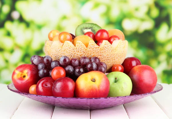 Surtido de frutas jugosas sobre mesa de madera, sobre fondo brillante — Foto de Stock