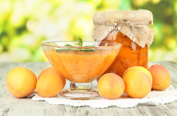 Marillenmarmelade im Glas und frischen Aprikosen, auf Holztisch, auf hellem Hintergrund — Stockfoto