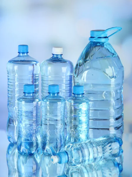 Water in different bottles on light background — Stock Photo, Image