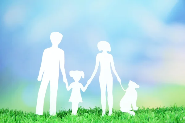 Family from paper on grass on bright background — Stock Photo, Image