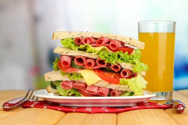 Huge sandwich on wooden table, on bright background — Stock Photo, Image