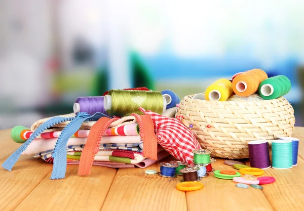 Rieten mand met toebehoren voor naaldwerk op houten tafel, op lichte achtergrond — Stockfoto