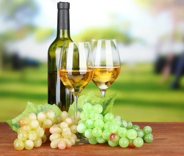 Ripe grapes, bottle and glasses of wine, on bright background — Stock Photo, Image