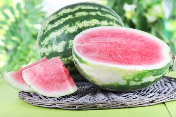 Ripe watermelons on wicker tray on wooden table on nature background — Stock Photo, Image