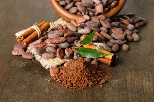 Boabe de cacao în castron, pudră de cacao și condimente pe fundal din lemn — Fotografie, imagine de stoc