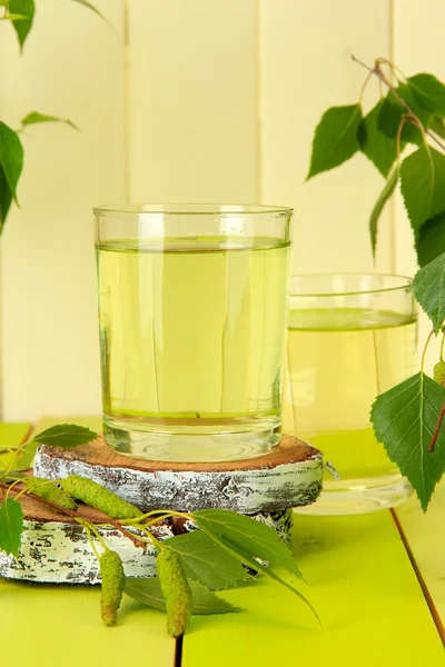 Стаканы березового сока на зеленом деревянном столе — стоковое фото