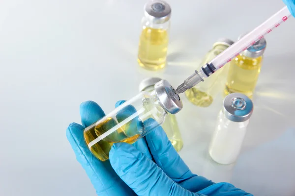 Medical bottles and syringe in hand on gray background — Stock Photo, Image