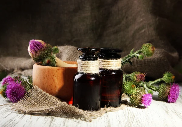 Medicine bottles and mortar with thistle flowers — Stock Photo, Image