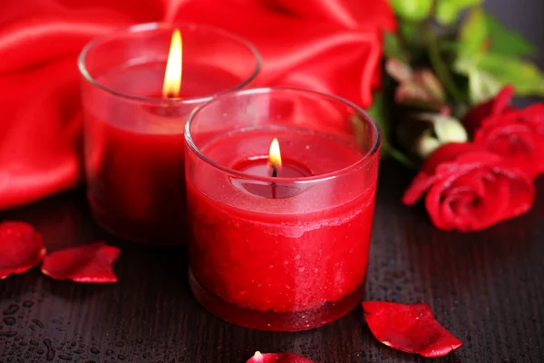 Krásné romantické červené svíčky s květinami, zblízka — Stock fotografie