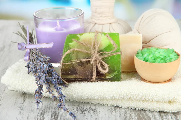 Stilleben med lavendel ljus, tvål, massage bollar, flaskor, tvål och färsk lavendel, på träbord på ljus bakgrund — Stockfoto