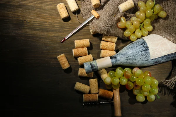 Vieja botella de vino, uvas y corchos sobre fondo de madera —  Fotos de Stock