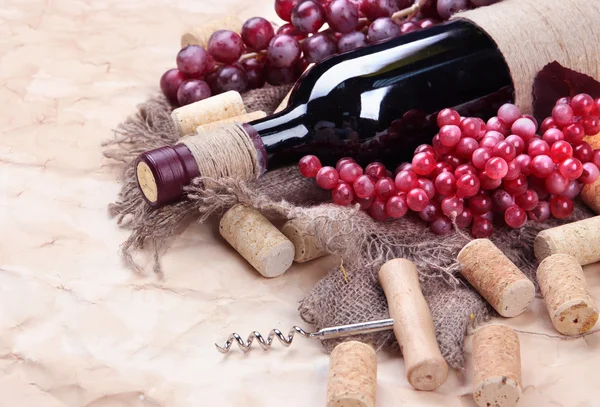 Botella de vino, uvas y corchos sobre papel viejo —  Fotos de Stock