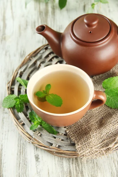 Czajnik i filiżanki herbaty ziołowej z mięty na drewnianym stole — Zdjęcie stockowe