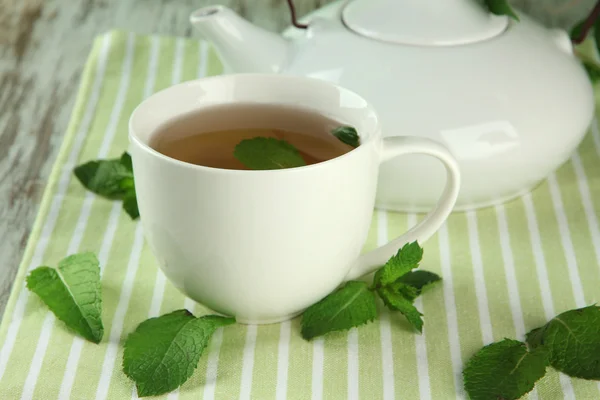 Teekanne und Tasse Kräutertee mit frischer Minze auf Holztisch — Stockfoto