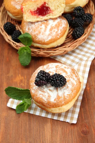 Tasty donuts with berries on wooden table — Stock Photo, Image