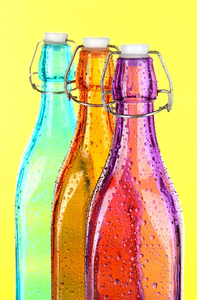 Bunte Flaschen auf gelbem Hintergrund — Stockfoto