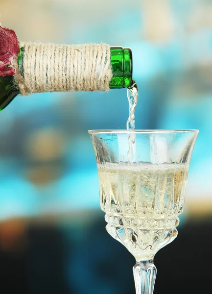 White wine being poured into wine glass, on bright background — Stock Photo, Image