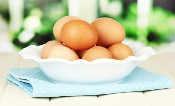 Яйця в тарілці на дерев'яному столі на фоні вікна — стокове фото
