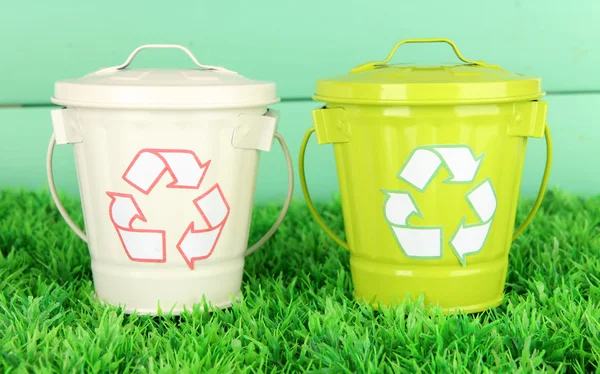 Recyklační koše na zelené trávě na barevné dřevěné pozadí — Stock fotografie