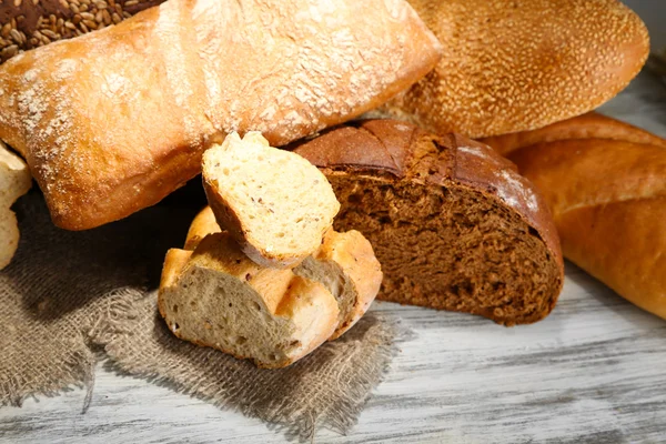 Much bread on sackcloth on wooden board — Stock Photo, Image