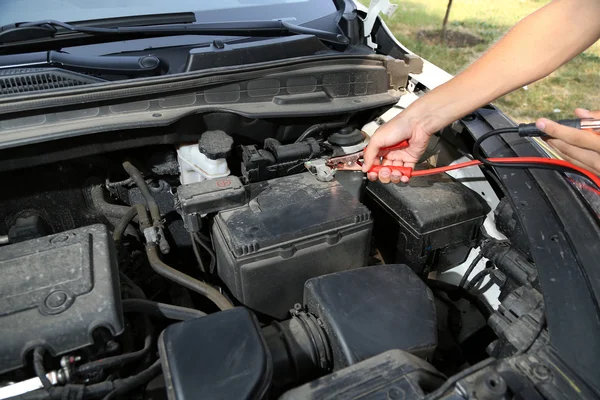 Car mechanic uses battery jumper cables to charge dead battery — Stock Photo, Image