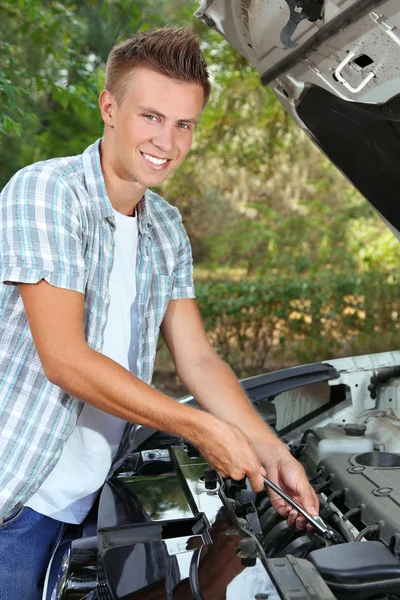 Motorista jovem reparando motor de carro ao ar livre — Fotografia de Stock