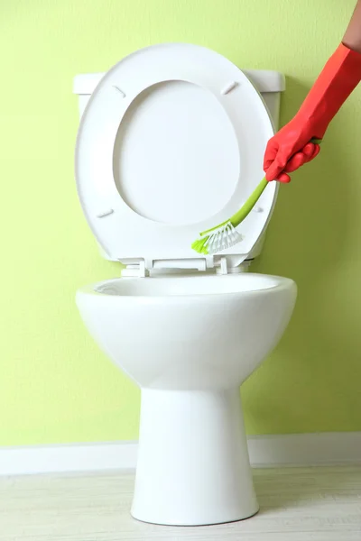 Mão de mulher com escova limpando um vaso sanitário em um banheiro — Fotografia de Stock