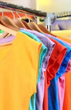 çeşitli ahşap askı raf arka plan üzerinde rahat t-shirt