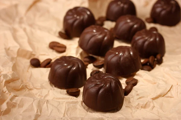 Schokoladenbonbons und Kaffeebohnen, auf beigem Papier Hintergrund — Stockfoto